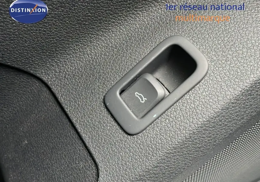 Bouton d'ouverture de coffre intégré dans le revêtement noir texturé de l'Audi Q2 35 2.0 TDI S-Line.