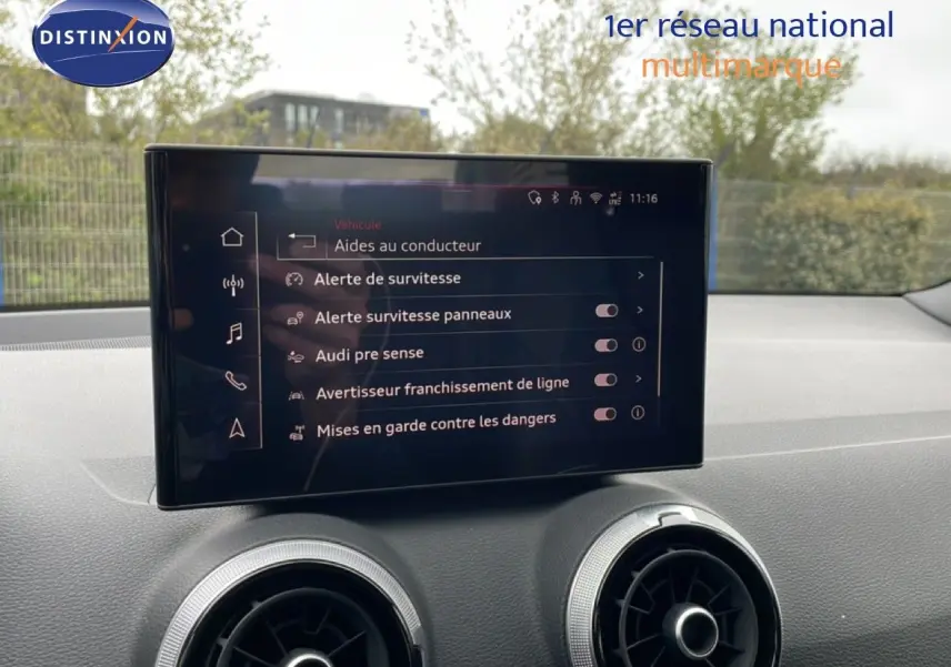 Vue intérieure du tableau de bord de l'Audi Q2 noir mito metal, avec écran tactile affichant les aides à la conduite.