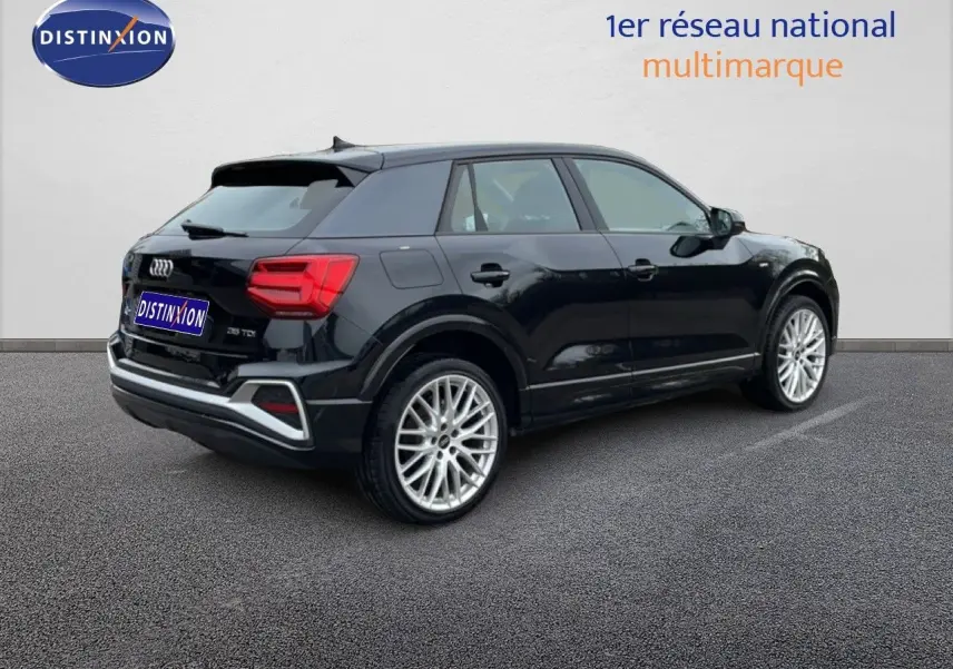Audi Q2 noir mito metal en 3/4 arrière droit, avec jantes alliage et détails S-Line visibles sur carrosserie.