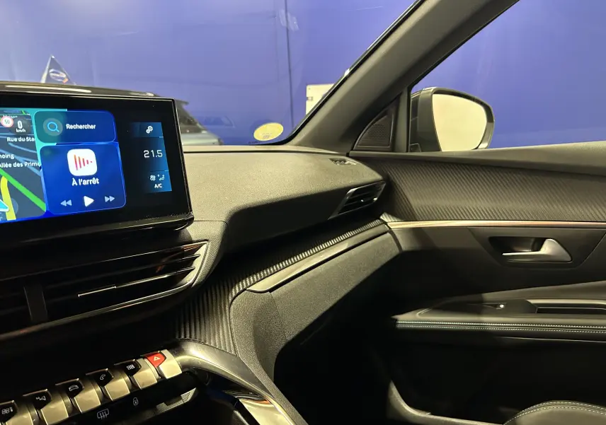 Vue intérieure côté passager du Peugeot 5008 2024, tableau de bord noir avec écran tactile et finitions carbone.