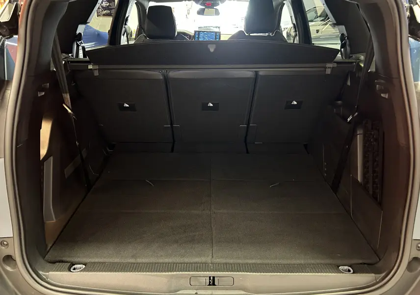Vue arrière du coffre spacieux du Peugeot 5008 Bleu Célèbes avec banquette rabattue et habillage intérieur noir.