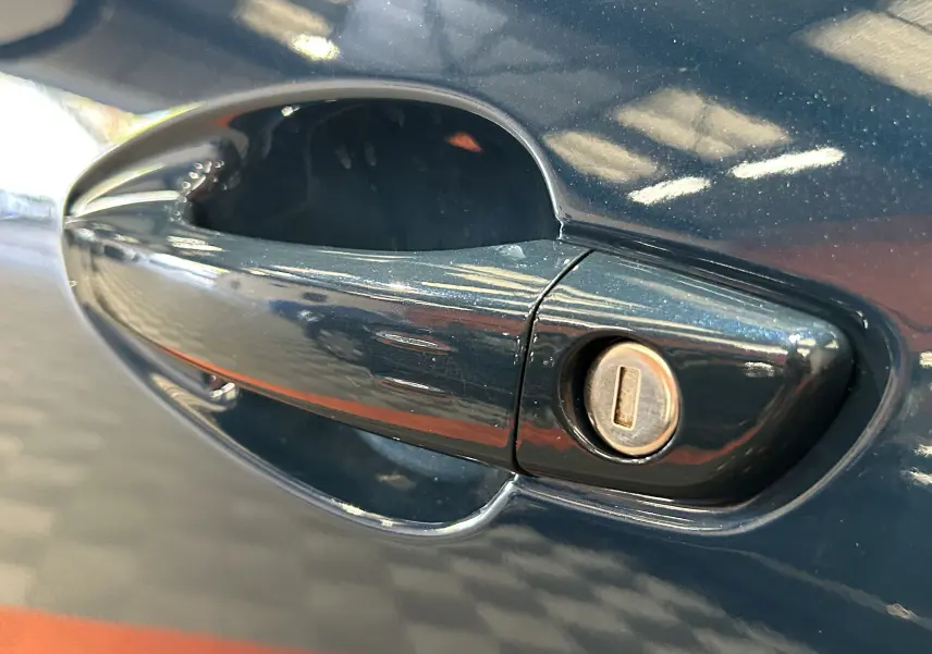 Gros plan sur la poignée de porte côté gauche bleu Célèbes du Peugeot 5008 II Ph.2 avec serrure visible.