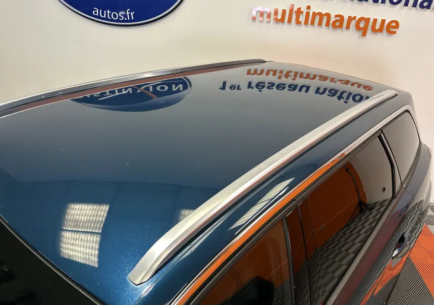 Vue en plongée du toit bleu célèbes du Peugeot 5008 avec barres de toit argentées et vitres teintées côté droit.
