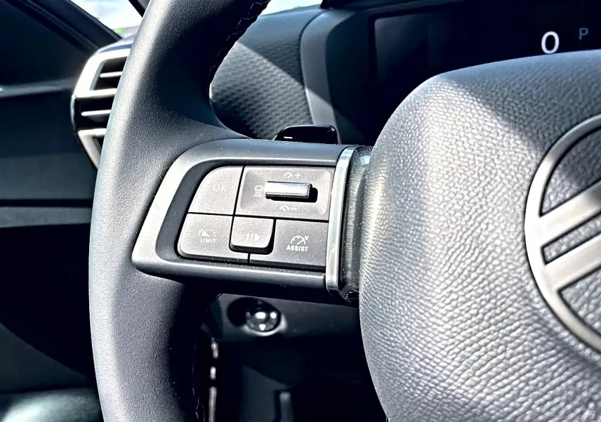Gros plan sur le côté gauche du volant cuir noir d'une Citroën C4 X 2025, avec commandes intégrées visibles.