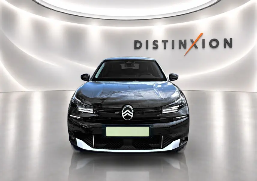 Vue frontale d'une Citroën C4 X noire 2025 avec logo distinctif et éclairage LED dans un showroom lumineux.