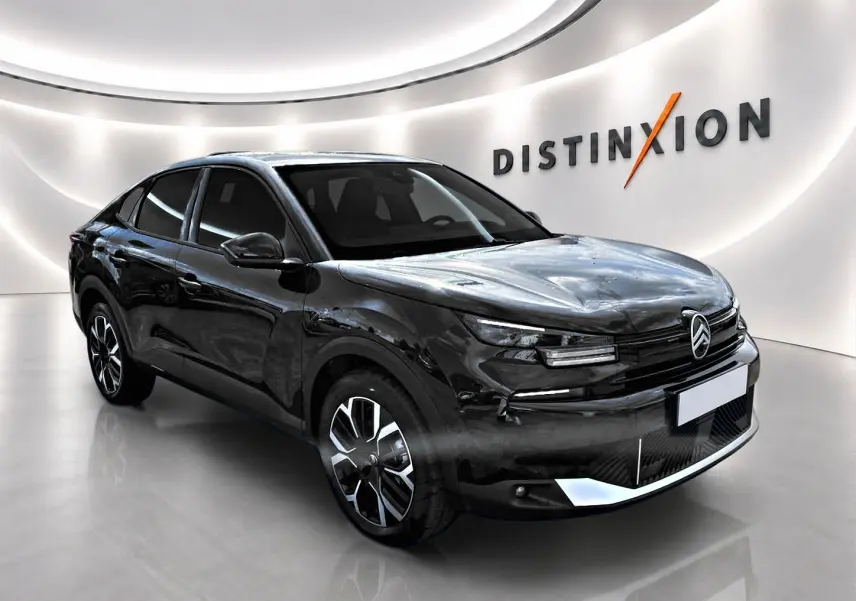 Citroën C4 X noire vue 3/4 avant droit en intérieur, avec jantes alu et signature lumineuse LED distinctive.