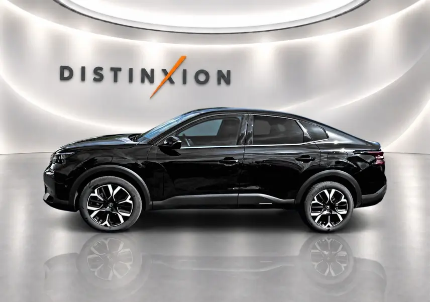 Profil côté gauche d'une Citroën C4 X noire 2025, avec jantes alu et vitres arrière surteintées en showroom lumineux.