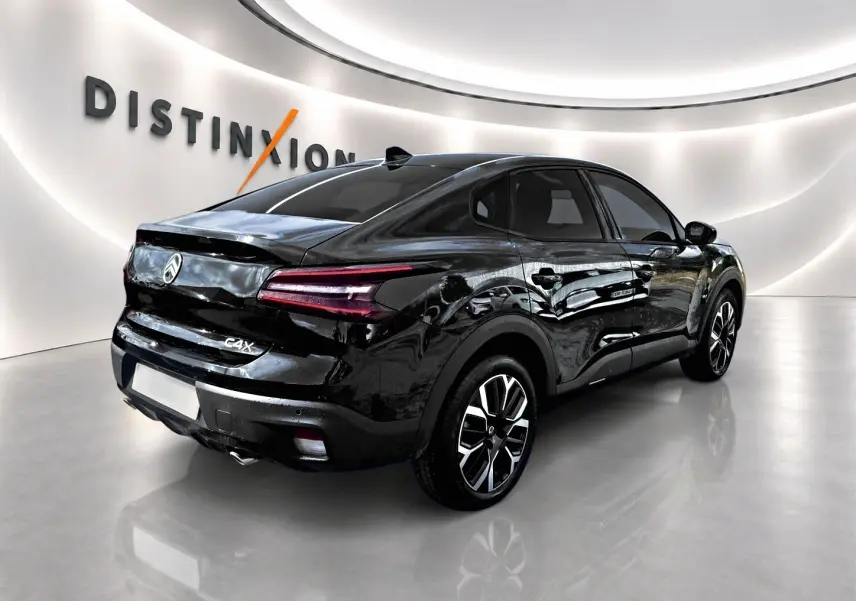 Vue 3/4 arrière droite d'une Citroën C4 X noire brillante avec feux arrière LED et jantes alu distinctives.