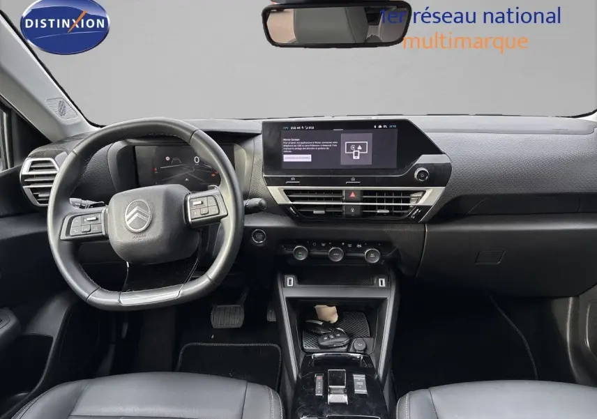 Vue intérieure frontale du tableau de bord et volant noir de la Citroën C4 Hybrid 2025 avec écran tactile central.