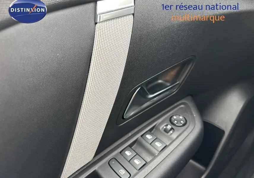 Détail intérieur de la porte côté gauche d'une Citroën C4 blanche, avec commandes des vitres et poignée noire.