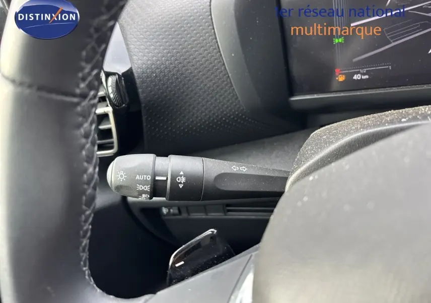 Gros plan sur la manette de clignotant gauche et partie du volant de la Citroën C4 Hybrid blanche, tableau de bord en arrière-plan.