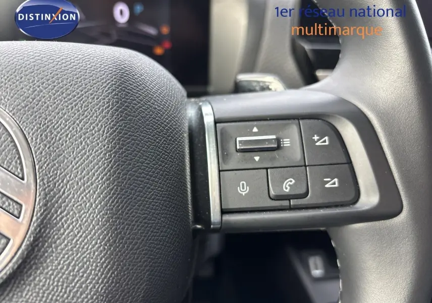 Gros plan sur les commandes au volant noir de la Citroën C4 Hybrid 145ch, intérieur beige visible en arrière-plan.