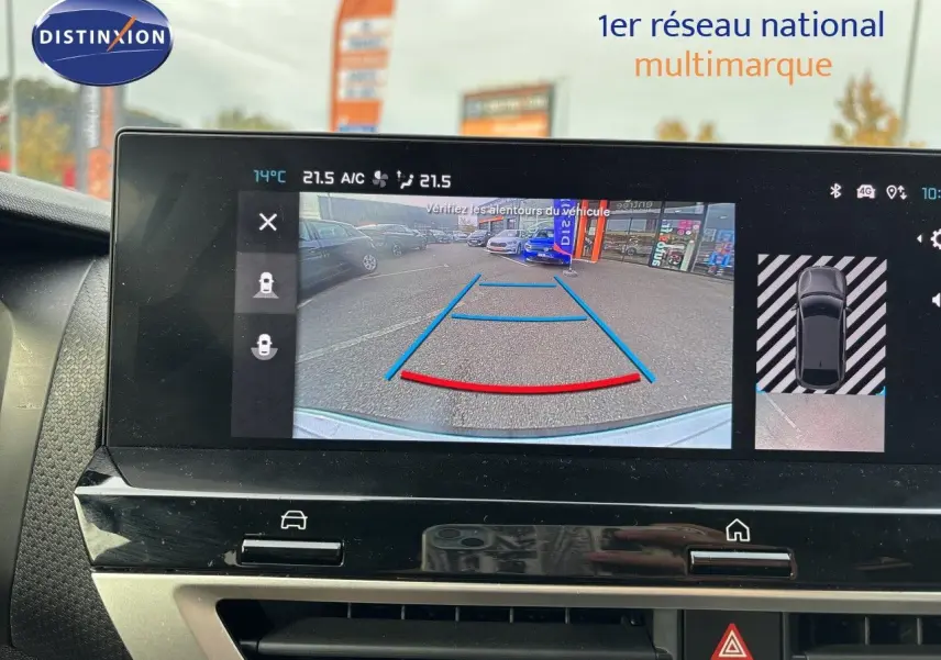 Écran intérieur montrant la caméra de recul d'une Citroën C4 blanc Okenite, vue arrière avec lignes de guidage colorées.
