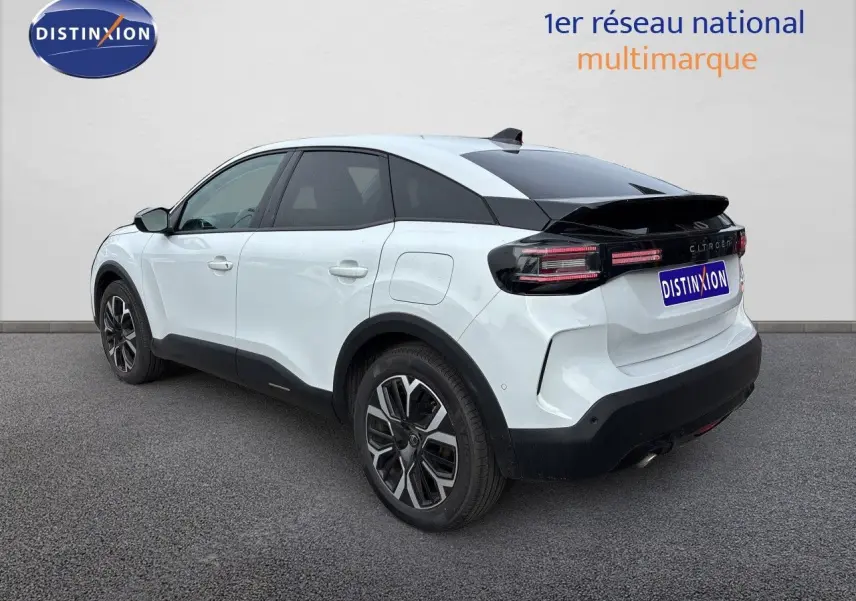 Vue 3/4 arrière droite d'une Citroën C4 hybride blanche Okenite Metal avec jantes bi-ton et toit noir.