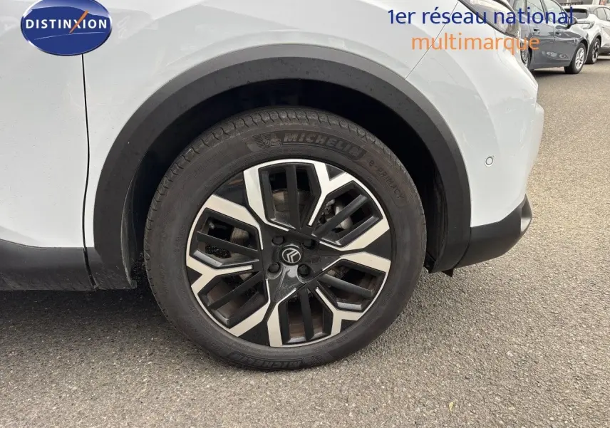 Gros plan sur la roue avant droite d’une Citroën C4 blanche Okenite Metal avec jante alliage noire et argent.