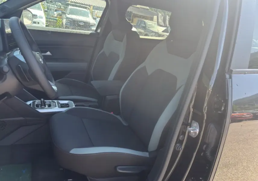 Vue intérieure côté gauche du Dacia Duster Hybrid-G 150 4x4 Extreme City 2026, sièges bicolores noir et gris nacré.
