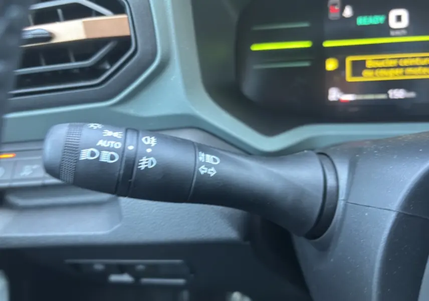 Gros plan sur la commande des feux à gauche du volant dans l’habitacle du Dacia Duster Hybrid-G 150 noir nacré 2026.