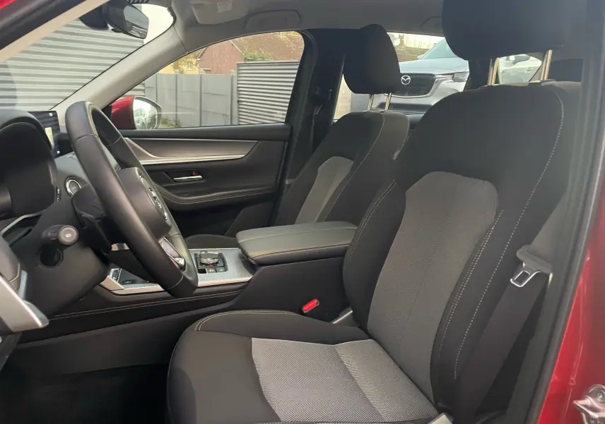 Vue intérieure côté conducteur du Mazda CX-60 Soul Red Crystal 2024, mettant en valeur les sièges tissu et la console centrale moderne.