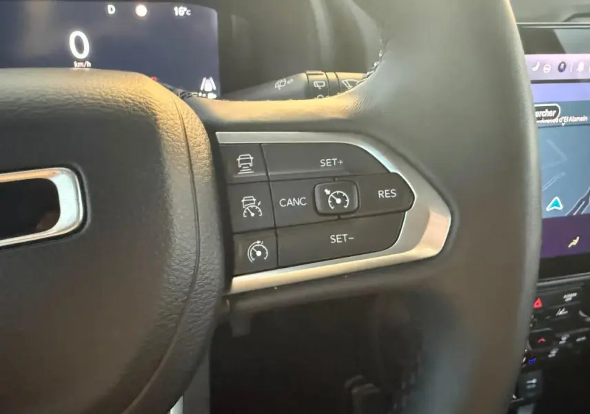 Gros plan sur les commandes du régulateur de vitesse au volant cuir noir du Jeep Renegade 2024 gris anthracite.