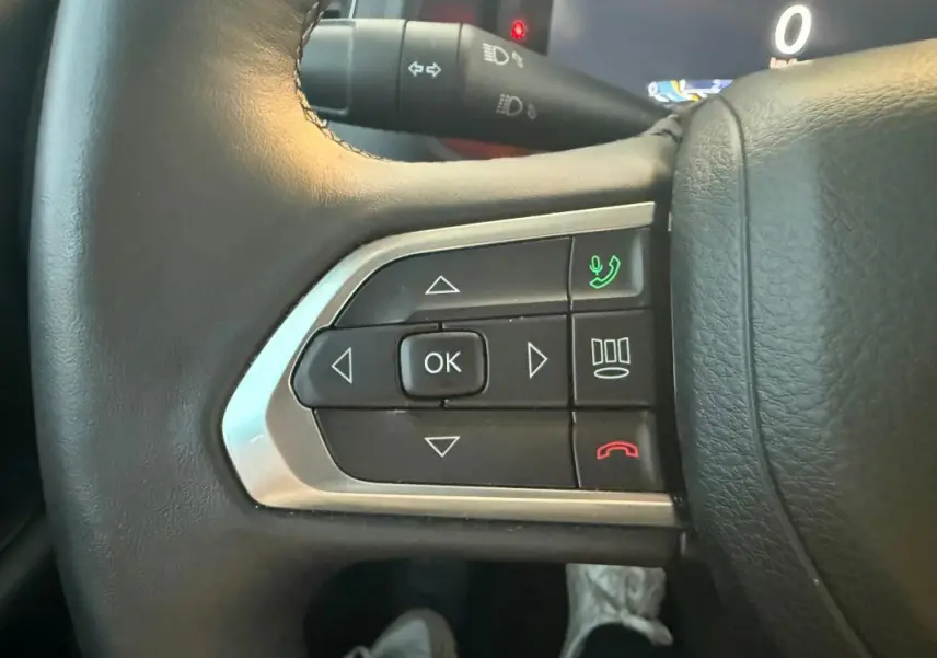 Gros plan sur les commandes du volant en cuir noir du Jeep Renegade 2024, avec boutons de téléphone et navigation.