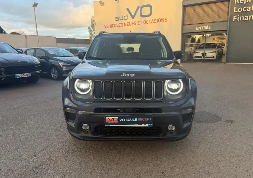 Vue frontale d'un Jeep Renegade gris anthracite 2024 avec phares allumés et barres de toit visibles.