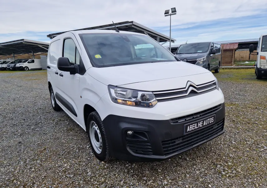 Vue 3/4 avant gauche d’un Citroën Berlingo blanc 2021 avec pare-chocs noir et jantes acier sur parking extérieur.