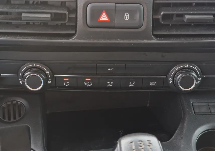 Gros plan sur la console centrale du Citroën Berlingo blanc 2021, montrant les commandes de climatisation et la boîte manuelle.