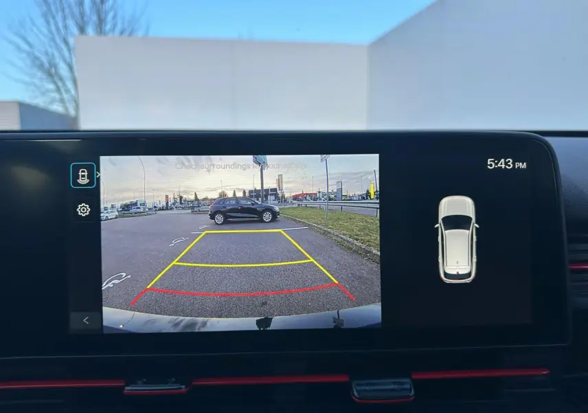Écran de caméra de recul affichant une Hyundai KONA grise en stationnement sur un parking extérieur.