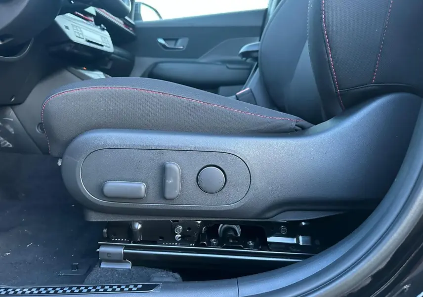 Gros plan sur le siège conducteur noir avec surpiqûres rouges du Hyundai Kona II 1.6 Hybrid N Line, côté gauche intérieur.