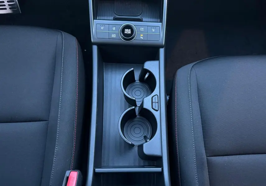 Gros plan sur la console centrale noire du Hyundai KONA 2026, montrant les porte-gobelets et commandes Drive Mode.