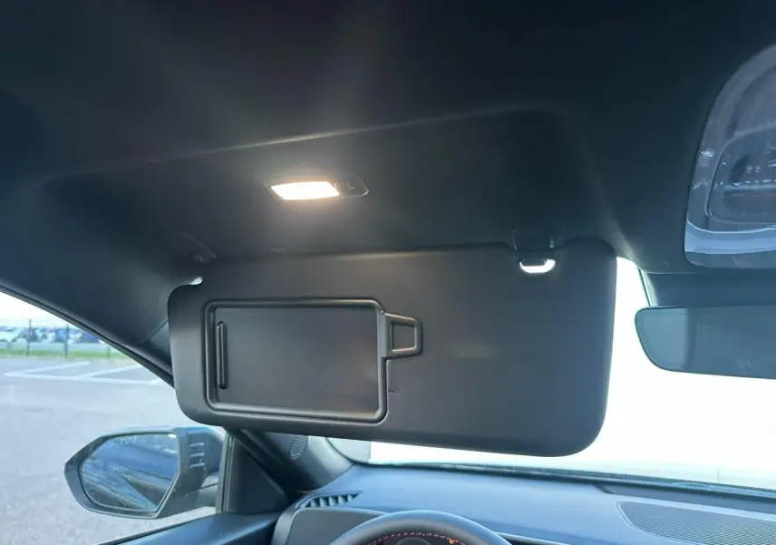 Intérieur du Hyundai KONA II hybride 2026 montrant le pare-soleil côté conducteur avec miroir, volant et rétroviseur.