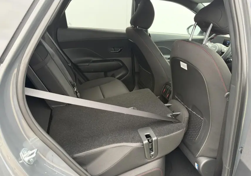 Vue intérieure côté gauche arrière du Hyundai KONA 2026 gris Ecotronic, siège rabattable et ceinture visible.
