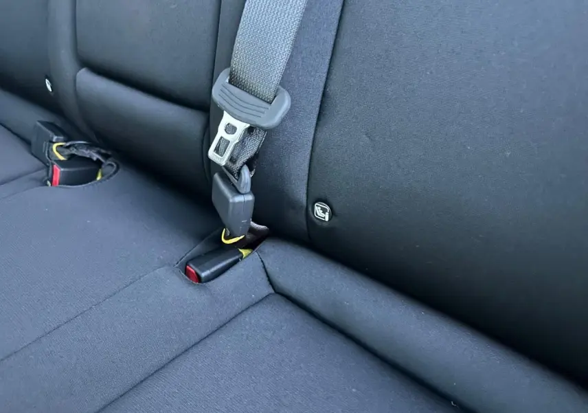 Gros plan sur la banquette arrière noire du Hyundai Kona II 1.6 Hybrid N Line avec ceinture et fixation Isofix visible.