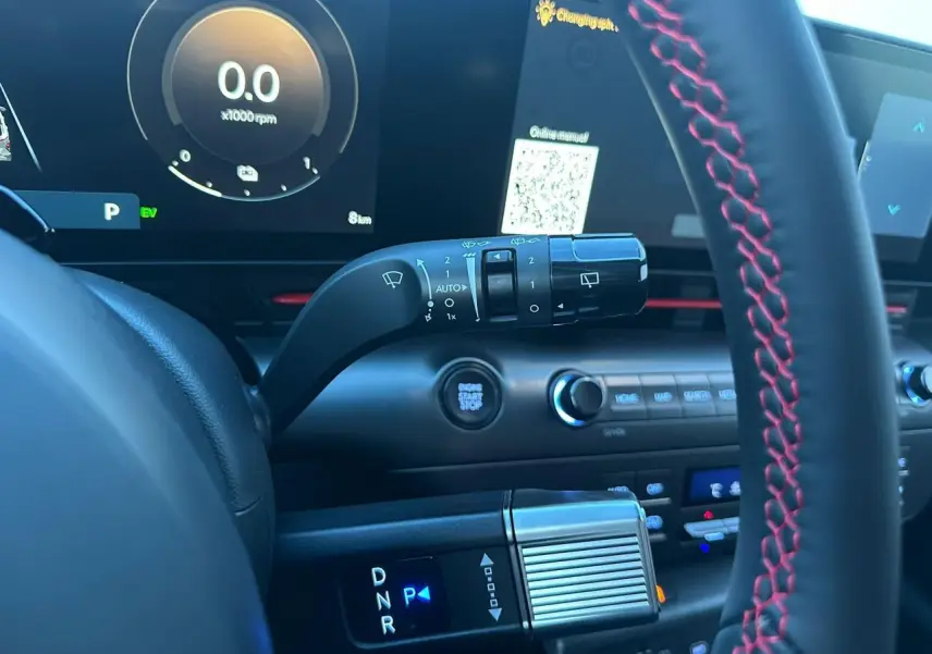 Gros plan intérieur sur le volant cuir noir avec surpiqûres rouges et levier de vitesses du Hyundai Kona II gris Ecotronic.