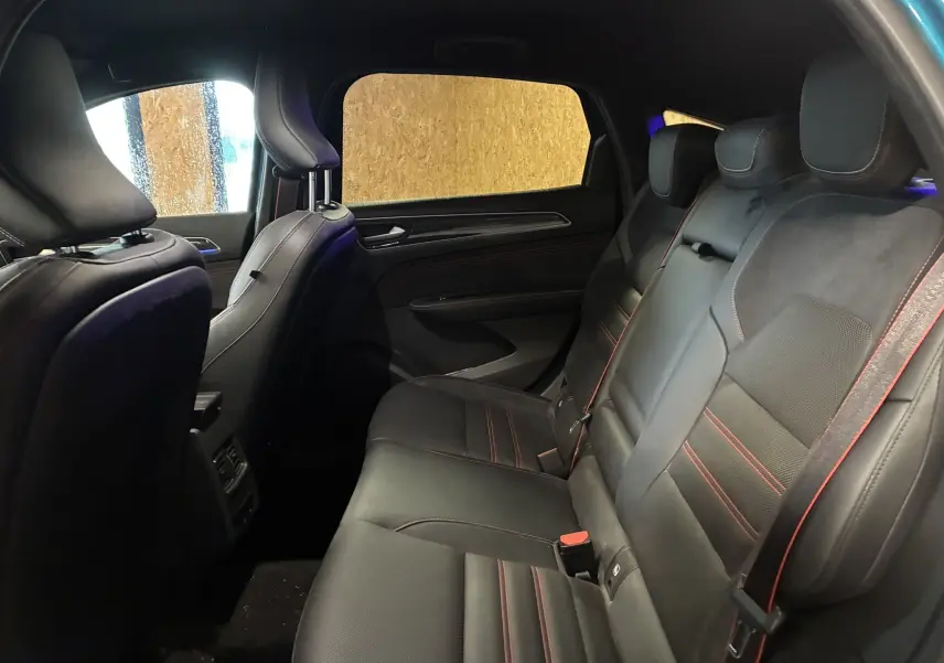 Vue intérieure côté gauche du Renault Arkana bleu 2021, sièges cuir noir avec surpiqûres rouges et volant multifonction.