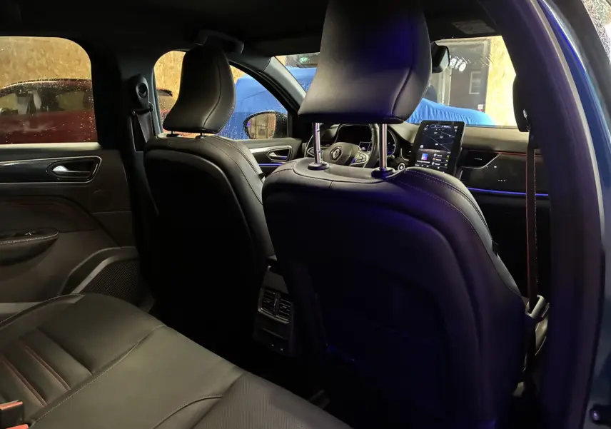 Vue intérieure de la porte arrière droite du Renault Arkana bleu, avec garniture noire et surpiqûres rouges visibles.