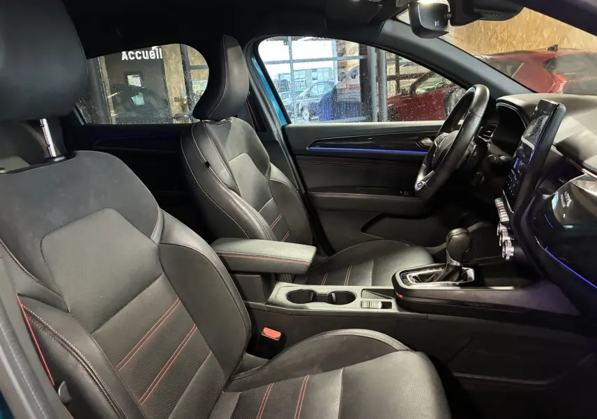 Coffre ouvert vu de l'arrière d'un Renault Arkana bleu, espace de chargement propre et éclairage latéral allumé.