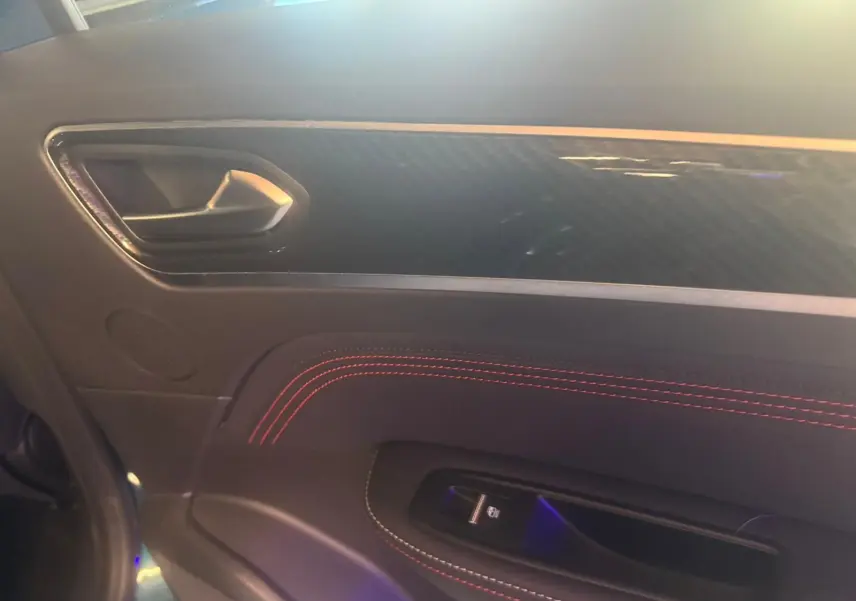 Détail de la porte intérieure côté gauche du Renault Arkana bleu, avec surpiqûres rouges et poignée argentée.
