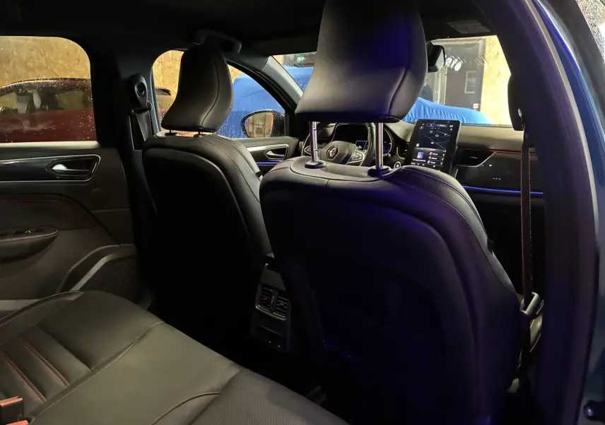 Vue intérieure arrière du Renault Arkana bleu 2021, mettant en valeur les sièges cuir noirs et l'écran tactile central.