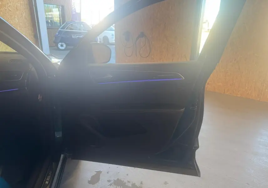 Portière avant gauche ouverte d'une Renault Arkana bleu 1.3 TCE 140 RS-LINE, avec éclairage d'ambiance violet visible.