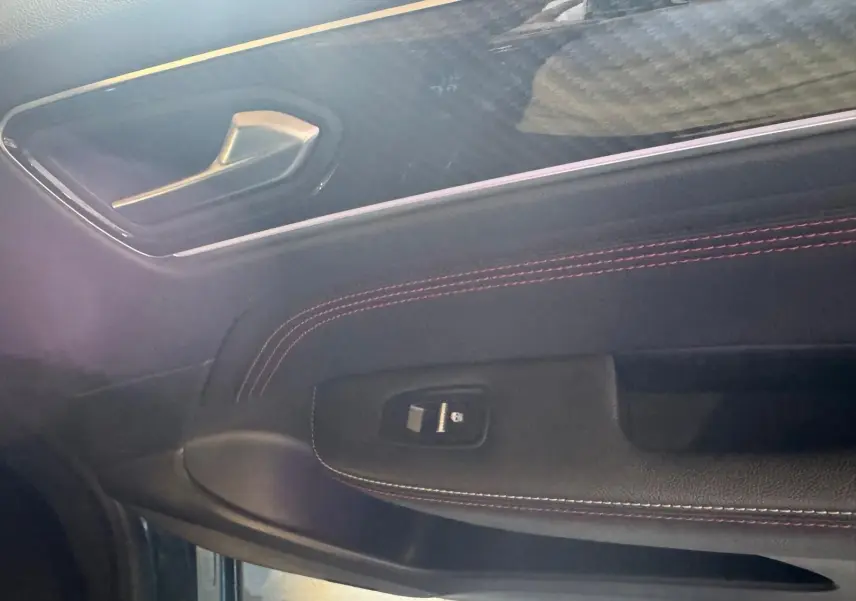 Détail de la porte côté gauche du Renault Arkana bleu 2021, avec surpiqûres rouges et commande de vitre électrique.