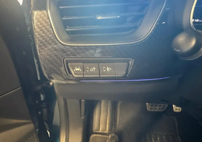 Détail intérieur côté gauche du tableau de bord du Renault Arkana bleu 1.3 TCE 140 RS-LINE avec commandes d’assistance et pédales visibles.