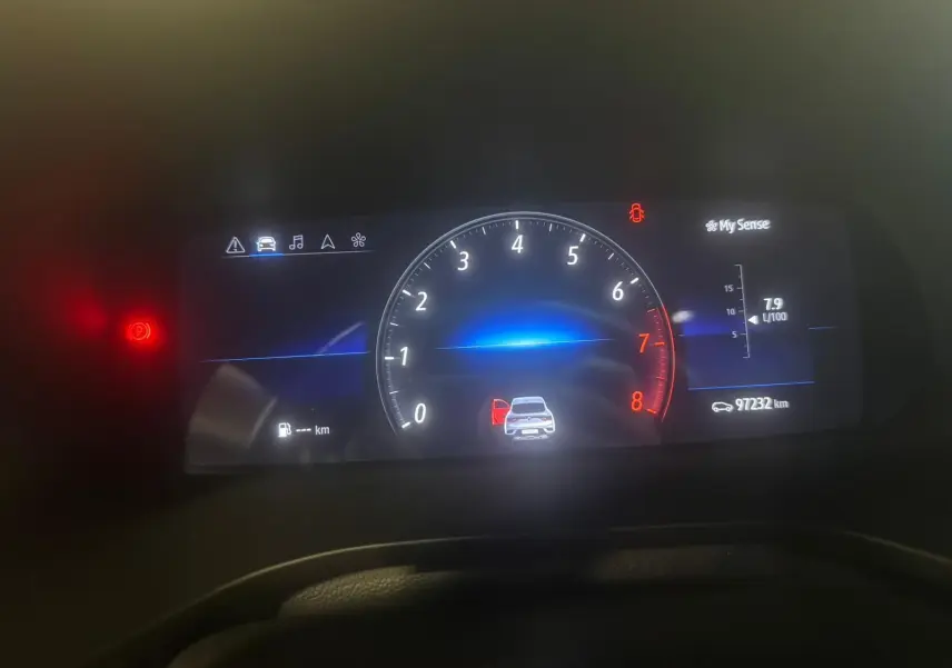 Tableau de bord numérique du Renault Arkana bleu, affichant le compte-tours, la consommation et une porte ouverte.