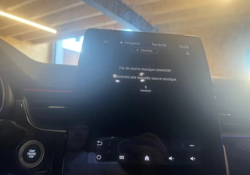 Écran tactile central du tableau de bord du Renault Arkana bleu, vue rapprochée en intérieur avec bouton start visible.