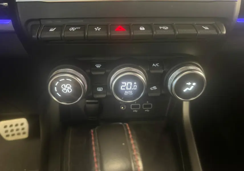 Gros plan sur la console centrale du Renault Arkana bleu 2021, montrant les commandes de climatisation et les boutons de fonction.