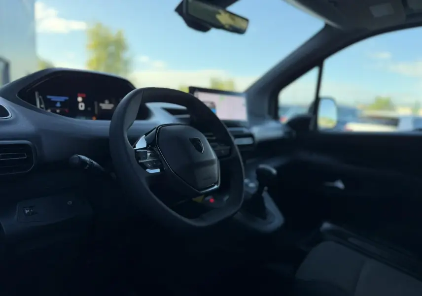 Vue intérieure côté conducteur du Peugeot Partner 2026, avec tableau de bord numérique et écran tactile central.