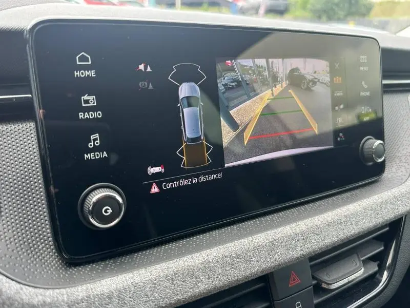 Écran tactile intérieur du Skoda Scala blanc, affichant la caméra de recul et l'alerte de distance.