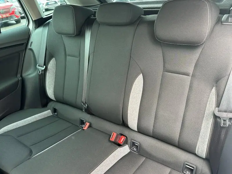Vue intérieure de la banquette arrière en tissu noir et gris du Skoda Scala blanc cristal 2025, avec ceintures de sécurité visibles.