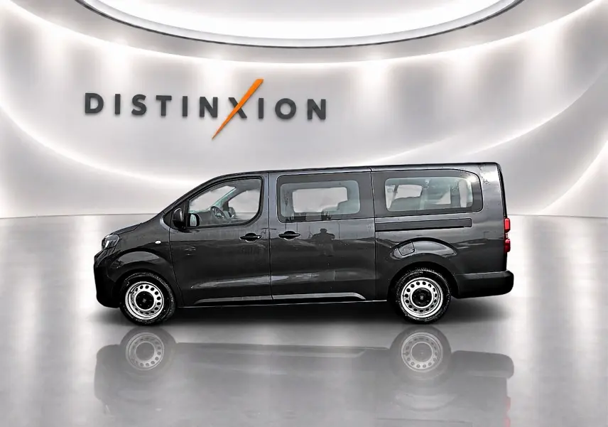 Vue de profil côté gauche du FIAT Scudo Combi gris titane avec porte latérale coulissante dans un showroom lumineux.