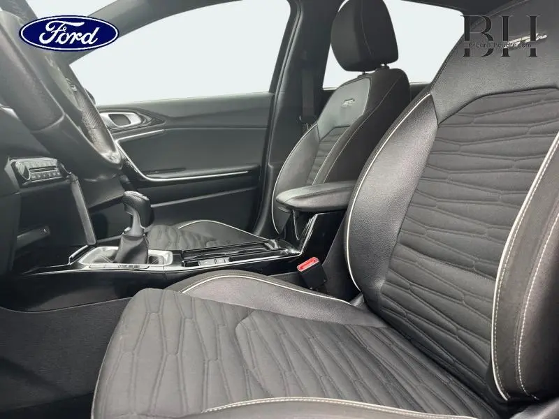 Vue intérieure côté conducteur de la Kia CEE'D SW 1.0 T-GDI GT Line 2023 avec sièges en cuir synthétique noir et console centrale brillante.